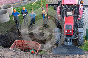 A team of builders is engaged in the repair of a sewer well. Reinforced concrete rings in the well. Trenchless re-laying or