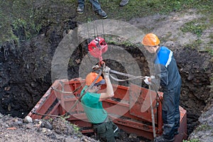 A team of builders is engaged in the repair of a sewer well. Reinforced concrete rings in the well. Trenchless re-laying or