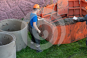 A team of builders is engaged in the repair of a sewer well. Reinforced concrete rings in the well. Trenchless re-laying or