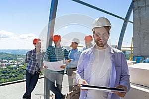 Team Of Builders On Site, Contractor Hold Plan Happy Smiling Over Apprentices Group Discussing Blueprint photo