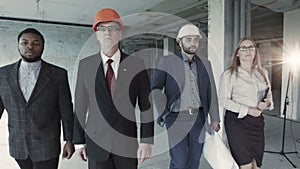 Team of builders in suits, hard hat, move, look directly into camera. Black man, aged engineer