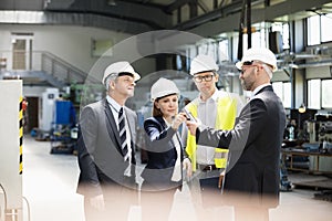 Team of business people examining machine part in metal industry