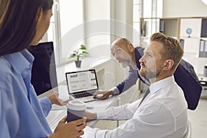 Team of business people having discussion while analyzing statistics graphs and charts in office