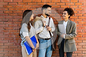 Team of business people talking in front of office building. Staff meeting quick briefing of office workers on motivational speech