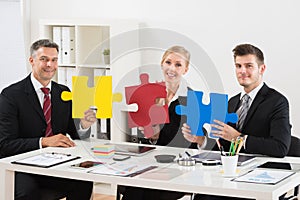 Team Of Businesspeople Holding Jigsaw Puzzle