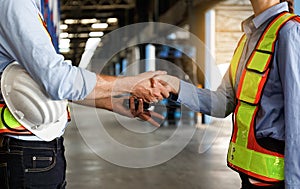 A team of Caucasian male and female engineers stood at the warehouse. shake hands to congratulate work on the goal