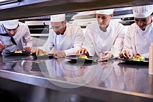Team of chefs garnishing dishes photo
