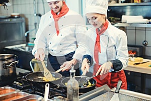 Team of chefs in a kitchen preparing fantastic food in pans