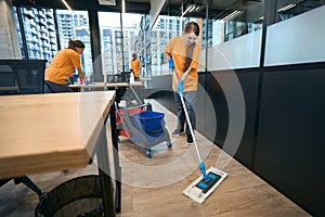 Team of cleaners work in coworking area, women clean all surfaces