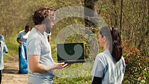 Team of climate and nature activists using laptop with greenscreen near a forest