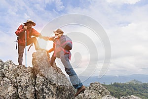 Team of climbers man and woman help each other on top of mountain, climbing hiking together, Young tourists with backpacks