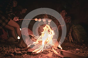 Team of climbers man and woman hiker camping.They are sitting around fire camp in the cave.