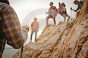 Team of climbers man and woman hiker holding hands to help each other up the hill with red flags for hiking for mountain climbing