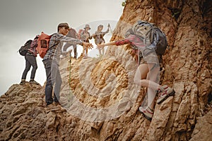 Team of climbers man and woman hiker holding hands to help each other up the hill with red flags for hiking for mountain climbing