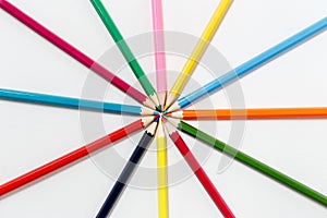 Team of colored pencils lined with rays on white background