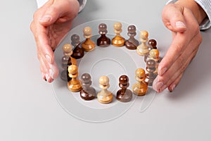 Team concept, leadership concept. Woman`s hands surrounding chess pawns standing in circle