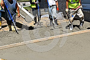 A team of concrete laborers work on the pouring of a new patio,
