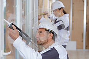 Team construction workers installing window in house