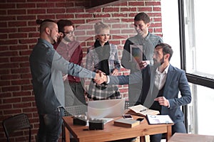 Team of copywriters and a handshake of business partners in a creative office.