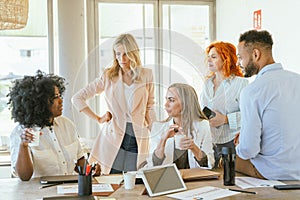 Team of coworkers gathering in the office while talking about a new project