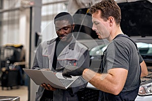 Team Of Diverse Auto Mechanic And Repairman Checking Diagnostics Results on Laptop.