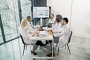 Team of diverse multiethnic medical experts or scientists, examining patient`s medical record, discussing about results