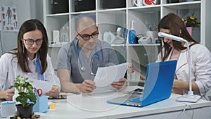 A team of doctors conferring, working with documents discussing.