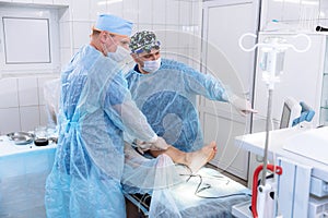 A team of doctors in the operating room conducts medical procedures. Surgeons in sterile clothing work in the hospital