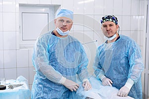 A team of doctors in sterile medical gowns perform surgery in a surgical room. Surgeon with an assistant after the