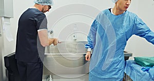 Team, doctors and washing hands, put on theatre gown or prepare to start surgery or operation in hospital. Surgeon