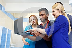 Multiracial team of young doctors working on laptop computer in medical office.