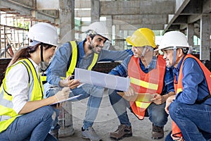 Team of engineer, architect, contractor and foreman meeting and consulting at construction building site with floor plan for real