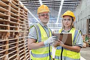 Team engineer carpenter wearing safety uniform and hard hat working holding clipboard checking quality of wooden products at