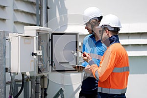 Team engineer inspect electrical control panel using tablet checking voltage, system connection and industrial infrastructure,