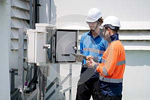 Team engineer inspect electrical control panel using tablet checking voltage, system connection and industrial infrastructure,