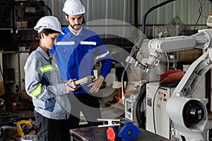 Team engineer using remote robot controller operate standing at automation robot arms machine in factory. technician maintenance