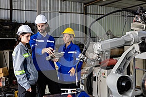 Team engineer using remote robot controller operate standing at automation robot arms machine in factory. technician maintenance