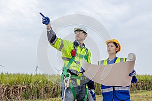 Team engineer of wind turbine worker pointing holding blueprint working about renewable energy at station energy power wind.