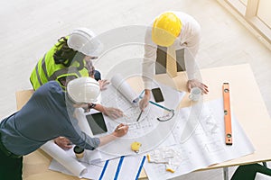 Team of engineers and architects working, planing, measuring layout of building blueprints in construction site. top view photo