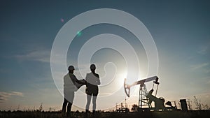 A team engineers discussing the maintenance of a oil pump field. Engineering team working in Oil refinery. Two workers