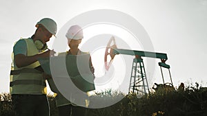 A team engineers discussing the maintenance of a oil pump field. Engineering team working in Oil refinery. Two workers