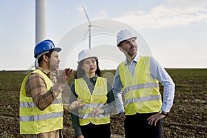 Team engineers standing on wind turbine field