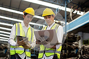 Team engineers, Worker wear uniform and helmet talk and using laptop checking engine parts in warehouse. workplace factory