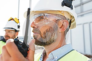 Team of engineers working on construction site. Two bearded builders control work process