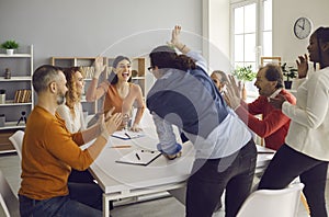 Team of excited diverse people celebrating their business success in office meeting