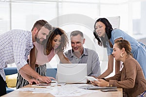 Team of executives discussing over laptop in the office