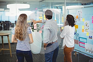 Team of executives discussing over sticky notes in office