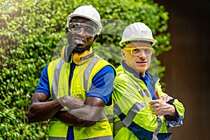 Team factory worker technician engineer men standing confidence with green working suite dress and safety helmet. Background of