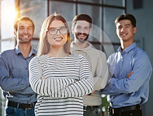 a team of four with a woman leader in the foreground stands in a modern office