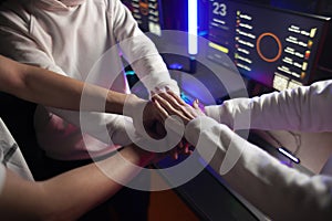 Team of gamers hold hands together before game in computer club, teamplay